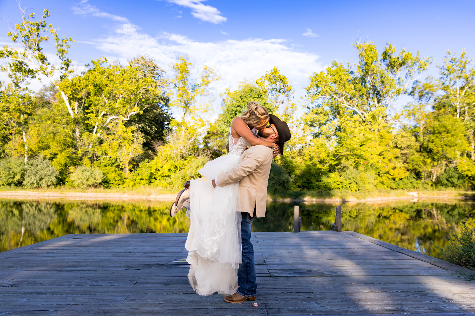 Wedding couple kiss on dock of lake